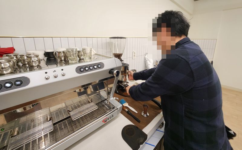 수강생이 그라인더에서 포터필터로 원두를 받는 모습